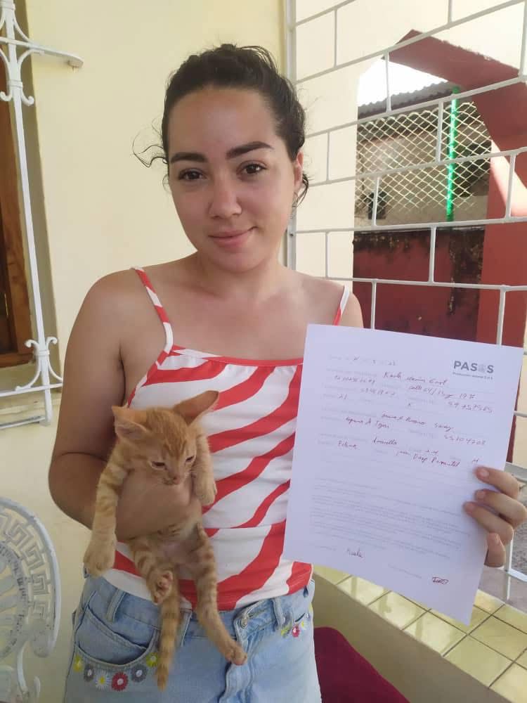 Una familia sonriendo junto a su gato recién adoptado en su nuevo hogar.